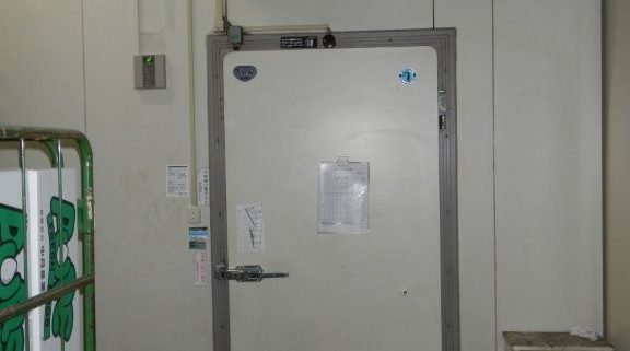 高気密仕様のプレハブ冷蔵庫ドアと管理ラベル類｜食品スーパーのバックヤードにて移設完了後の様子