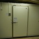 神奈川県伊勢原市の惣菜店バックヤードに新設したプレハブ冷蔵庫の外観。高断熱パネルと気密性の高い専用ドアを備え、衛生管理と保冷力を両立。