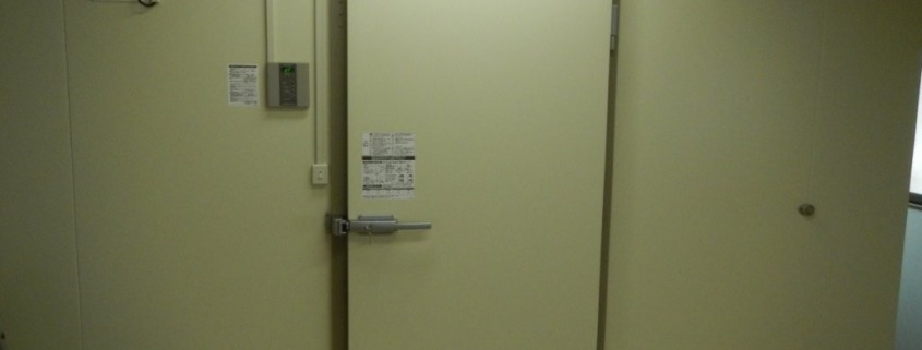 神奈川県伊勢原市の惣菜店バックヤードに新設したプレハブ冷蔵庫の外観。高断熱パネルと気密性の高い専用ドアを備え、衛生管理と保冷力を両立。